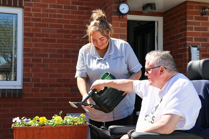 carer helping a client water flowers